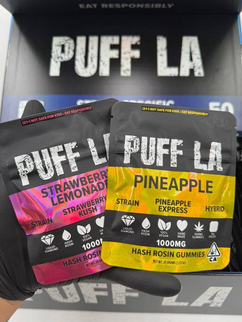 Puff LA Edibles 1000mg THC Cluster Gummies packaging display showing Strawberry Blueberry and Grape flavors